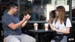 Dua orang penyandang tuli berbicara dengan bahasa isyarat di gerai Starbucks di Washington DC (foto: ilustrasi). 