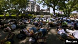 Anak-anak sekolah Jepang melakukan aksi teatrikal berpura-pura sebagai korban bom atom di depan 'Kubah Bom Atom' di kota Hiroshima, Rabu (5/8).