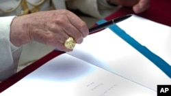 FILE - Pope Francis follows in the footsteps of his predecessor, Pope Benedict XVI, seen here signing a book during a visit to the Ardeatine Caves Memorial in Rome, March 27, 2011.