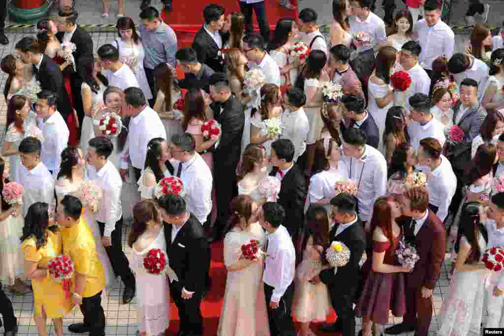 Newlywed couples kiss during a mass wedding in Kuala Lumpur, Malaysia. A mass wedding ceremony was held for 99 couples on the ninth day of the ninth month, considered an auspicious date, at a Chinese temple in the city. 