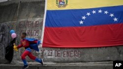 Un niño vestido como "SuperBigote" corre frente a una bandera venezolana en el barrio de Catia en Caracas, el 28 de febrero de 2022. 