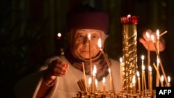 FILE - A worshipper lights a candle during a Christmas service at the Saints Florus and Laurus the Martyrs church in Moscow, on January 6, 2024.