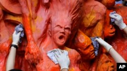 Mahasiswa membersihkan patung "Pillar of Shame", peringatan bagi mereka yang tewas dalam penumpasan Tiananmen 1989, di Universitas Hong Kong Selasa, 4 Juni 2019. (Foto: AP)