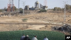 Warga duduk di depan menara pengawasan militer Israel sambil memperhatikan Israel mencari lima militan Palestina yang tewas di terowongan yang dihancurkan Israel dekat perbatasan Khan Younis, jalur Gaza, Jumat, 3 November 2017.