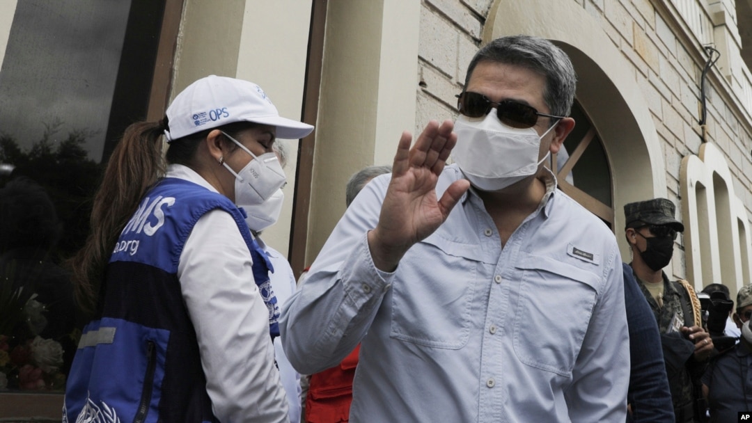 El presidente hondureño Juan Orlando Hernández saluda a su llegada a una base aérea para recibir un envío de la vacuna AstraZeneca COVID-19 a través del programa COVAX, en Tegucigalpa, Honduras, el sábado 13 de marzo de 2021.
