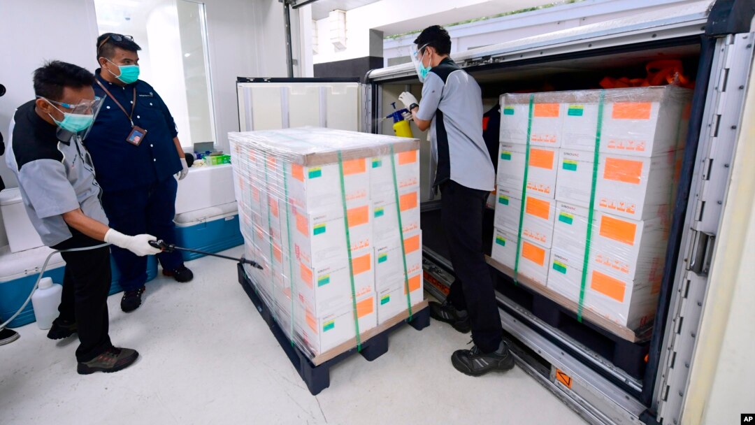 Para petugas menyemprotkan disinfektan pada kotak berisi vaksin eksperimental untuk Covid-19 produksi perusahaan China Sinovac, setibanya di fasilitas perusahaan farmasi milik negara Bio Farma, di Bandung, Jawa Barat, 7 Desember 2020.