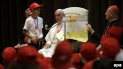 Le pape François, au centre, et le cardinal Gianfranco Ravasi, à droite, montrent un dessin représentant des migrants lors d’une rencontre avec quelque 400 enfants venus de la Calabre, au Vatican, 28 mai 2016. epa/ GREGORIO BORGIA / POOL