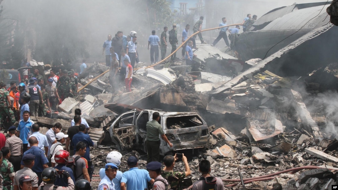 Para petugas pemadam kebakaran dan militer memeriksa lokasi jatuhnya pesawat Air Force Hercules C-130 di Medan, Sumatera Utara (30/6). (AP Photo/Gilbert Manullang).
