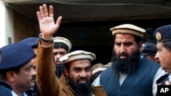 FILE - Police officers escort Zakiur Rehman Lakhvi, center, the main suspect of the Mumbai terror attacks in 2008, after his court appearance in Islamabad, Pakistan, Jan. 1, 2015.