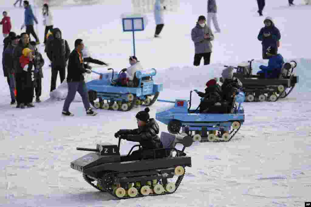 Children ride military tank-styled snow karts at a park made with artificial snow during the Longtan Park Temple Fair on the second day of Lunar New Year in Beijing.