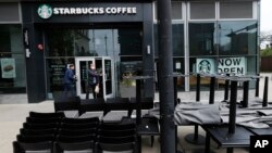 Patrons to a Starbucks in the Chicago neighborhood of Hyde Park walk past stacked chairs and tables, May 21, 2020.