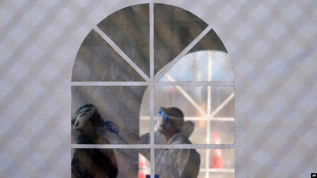 A health care worker gives a test at a COVID-19 testing site during the coronavirus outbreak in San Francisco, California, Nov. 16, 2020. 