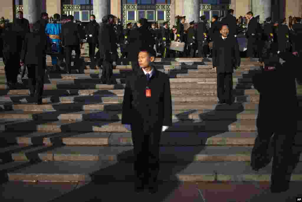 A soldier dressed as an usher, front, guards the stairs to the Great Hall of the People, while a Chinese Communist Party delegate poses for photos ahead of the closing ceremony of the 18th Communist Party Congress in Beijing, China, November 14, 2012. 