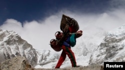 Seorang porter Nepal berjalan dengan barang bawaannya dari base camp Everest di Nepal, 3 Mei 2011. 