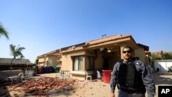 A policeman stands in front of a house hit by a rocket fired from Gaza Strip in Netivot, Israel, after it was hit by a rocket fired from Gaza Strip, Tuesday, Nov. 12 2019. 