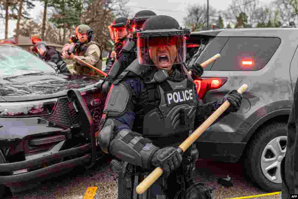 Police officers take cover as they clash with protesters after an officer shot and killed a black man in Brooklyn Center, Minneapolis, April 11,2021.