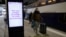 A man wearing a protective face mask walks past an announcement for travelers to protect themselves and others from the coronavirus, at Montparnasse train station in Paris, France, March 13, 2020.