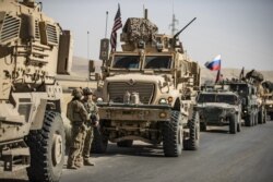 U.S. military vehicles enclose Russian military vehicles in the northeastern Syrian town of Malikiyah at the border with Turkey, June 3, 2020.
