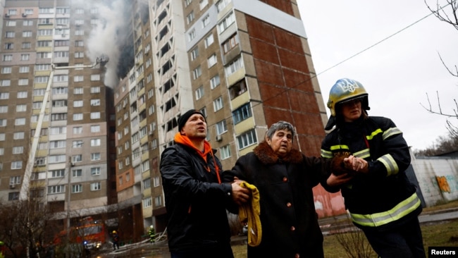 Firefighters help a woman from a building damaged during a Russian missile strike in Kyiv, Ukraine, Feb. 7, 2024.