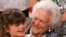FILE - Mia Trumble, 7, sits on Barbara Bush's lap after the former first lady spoke at ceremony for Literacy Maine, June 15, 2011, in Biddeford, Maine. 