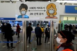 FILE - A social distancing sign is seen as people wait to buy tickets at the Seoul Railway Station in Seoul, South Korea, Nov. 13, 2020.