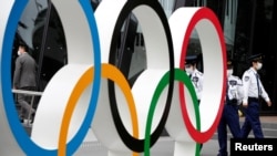 資料照：日本保安在東京日本奧委會總部外看守奧運標識（2021年5月18日）