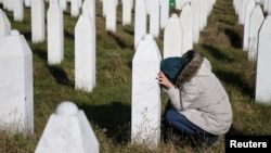 FILE - A woman visits a grave of her family members in the memorial center Potocari near Srebrenica, Bosnia and Herzegovina, after the court proceedings of former Bosnian Serb general Ratko Mladic, Nov. 22, 2017.