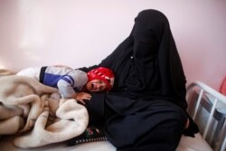 FILE - A child cries as he lays on the lap of his mother at a cholera treatment center in Sana'a, Yemen, Oct. 29, 2016.