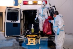 FILE - EMTs cleanse their materials outside Memorial West Hospital where coronavirus disease (COVID-19) patients are treated, in Pembroke Pines, Florida, July 13, 2020.