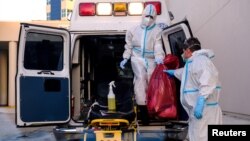 FILE - EMTs cleanse their materials outside Memorial West Hospital where coronavirus disease (COVID-19) patients are treated, in Pembroke Pines, Florida, July 13, 2020. 