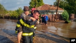 A rescuer carries a woman in Pechea, Romania, on Sept. 14, 2024, after torrential rainstorms left scores of people stranded in flooded areas. (Romanian Emergency Services via AP)