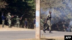 Armed Malawian policemen walk through a cloud of teargas to disperse supporters of The Malawi Congress Party (MCP) in Lilongwe on June 6, 2019, as they attempt to prevent them from regrouping on the second day of protests against President Peter Mutharika's ascension to power.