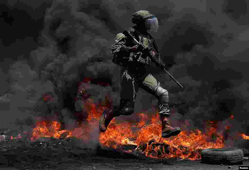 An Israeli border police member jumps during a Palestinian protest against Israel's plan to annex parts of the Israeli-occupied West Bank, in Kafr Qaddum near Nablus.