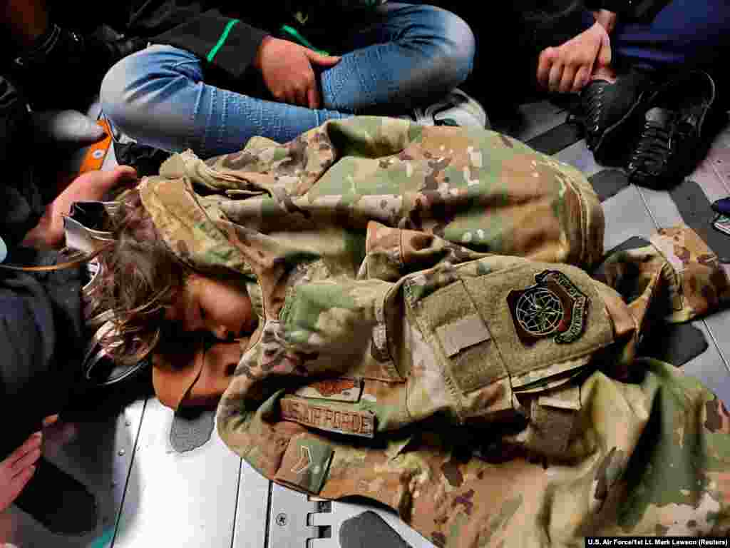 An Afghan child sleeping on the cargo floor of a U.S. Air Force C-17&nbsp; is kept warm by the clothing of Airman First Class Nicolas Baron, C-17 loadmaster, during an evacuation flight from Kabul, Afghanistan, Aug. 18, 2021.