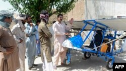 Muhammad Fayyaz (kanan) berbicara dengan para pengunjung sambil berdiri di sebelah pesawat mini hasil karyanya di Desa Tabur, Provinsi Punjab, 8 April 2019. (Foto: AFP)
