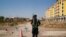 FILE - A Chinese police officer takes his position by the road near what is officially called a vocational education centre in Yining in Xinjiang Uighur Autonomous Region, China, Sept. 4, 2018. 