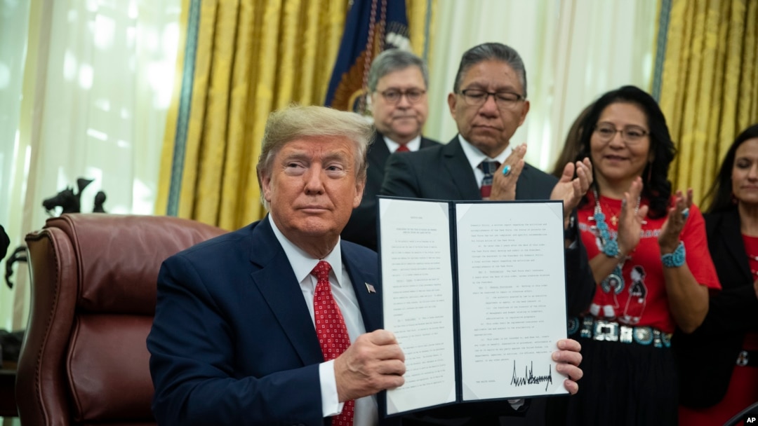 President Donald Trump shows an executive order establishing the Task Force on Missing and Murdered American Indians and Alaska Natives, in the Oval Office of the White House, Tuesday, Nov. 26, 2019, in Washington. (AP Photo/ Evan Vucci)