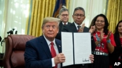 President Donald Trump shows an executive order establishing the Task Force on Missing and Murdered American Indians and Alaska Natives, in the Oval Office of the White House, Tuesday, Nov. 26, 2019, in Washington. (AP Photo/ Evan Vucci)