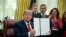President Donald Trump shows an executive order establishing the Task Force on Missing and Murdered American Indians and Alaska Natives, in the Oval Office of the White House, Tuesday, Nov. 26, 2019, in Washington. (AP Photo/ Evan Vucci)