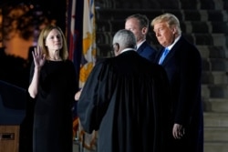 President Donald Trump watches as Supreme Court Justice Clarence Thomas administers the Constitutional Oath to Amy Coney Barrett on the South Lawn of the White House in Washington, Oct. 26, 2020, after Barrett was confirmed by the Senate earlier.