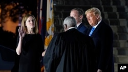 President Donald Trump watches as Supreme Court Justice Clarence Thomas administers the Constitutional Oath to Amy Coney Barrett on the South Lawn of the White House in Washington, Oct. 26, 2020, after Barrett was confirmed by the Senate earlier.