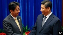 日本首相安倍晉三（左）和中國國家主席習近平（右）在亞太經合組織舉行期間在人民大會堂握手。