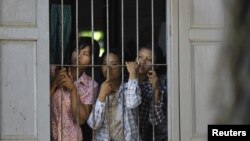 Burmese farmers look at police from inside a monastery in protest against the seizing of farmland across 26 villages for a copper mine project in Sarlingyi Township, September 12, 2012. 