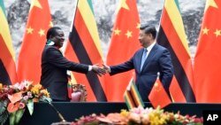 Zimbabwean President Emmerson Mnangagwa, left, shakes hands with Chinese President Xi Jinping as they pose for the media after a signing ceremony at the Great Hall of the People in Beijing, China, April 3, 2018.
