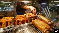 ARSIP – Seorang pekerja menjual Pretzel Dog di sebuah gerai Auntie Anne. Restoran waralaba tersebut telah diminta oleh otoritas Islam untuk mengganti nama menu Pretzel Dog yang terkenal, yang tidak mengandung daging anjing, karena nama tersebut berpotensi membingungkan konsumen kaum Muslim. Kuala Lumpur, Malaysia. (foto: AP Photo/Vincent Thian)