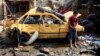 An Iraqi boy stands near a destroyed car at the scene of a car bomb attack in Baghdad's northern Kazimyah neighborhood, Feb. 8, 2013.