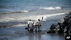 Trabajadores realizan labores de limpieza tras un derrame de petróleo que llegó a la playa de Rockly Bay, en Scarborough, suroeste de Tobago, Trinidad y Tobago, el domingo 11 de febrero de 2024.