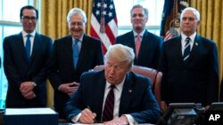 President Donald Trump signs the coronavirus stimulus relief package in the Oval Office at the White House in Washington, March 27, 2020.