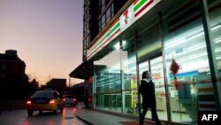 资料照：一名女子走过北京街头一家7-11便利店。（2012年1月3日）