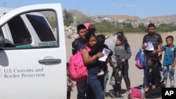 In this April 2019, frame from video, migrants turn themselves in to border agents in El Paso, Texas, after crossing the US - Mexico border.